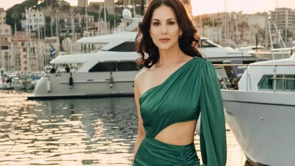 "Sunny Leone turns heads and steals the spotlight at Cannes 2023 with her breathtaking satin gown for the premiere of her movie 'Kennedy.' See her one-shoulder light pink gown and stunning accessories as she graces the red carpet alongside director Anurag Kashyap and co-star Rahul Bhat."